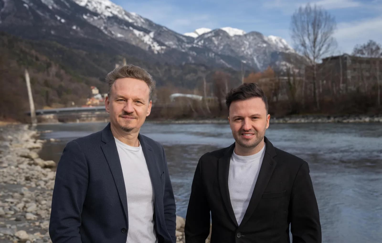 Das Team von CHARONIUM an einem Fluss vor verschneiten Bergen in Tirol